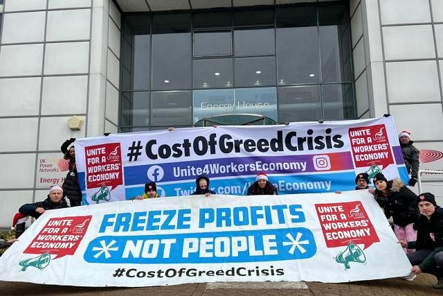Workers holding sign saying 'Freeze profits, not people'.